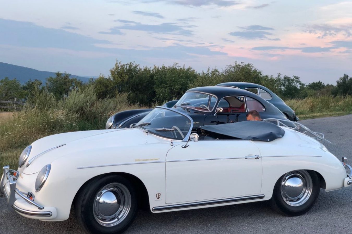 Ein weißer Porsche und zwei schwarze Porsche von der Seite